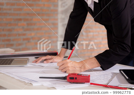 Closeup hands young caucasian architect woman looking laptop and working drawing blueprint. 99962778
