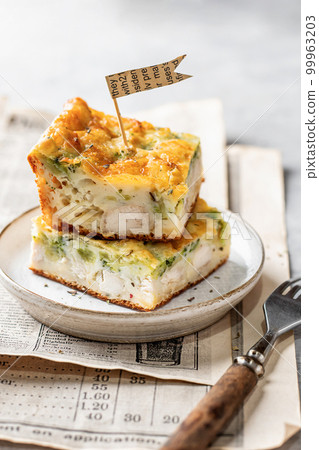 Chicken broccoli cheesy sliced casserole on a plate with cutlery on gray background. Healthy food Chicken broccoli cheesy sliced casserole on a plate with cutlery on gray background. Healthy food 99963203