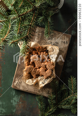 Christmas cookies or gingerbreads of patterned animal shapes on in wooden box on green wooden table. Xmas or new year rustic composition with fir tree , top view 99963210