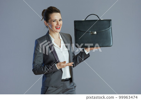 happy elegant woman worker in gray suit isolated on gray 99963474