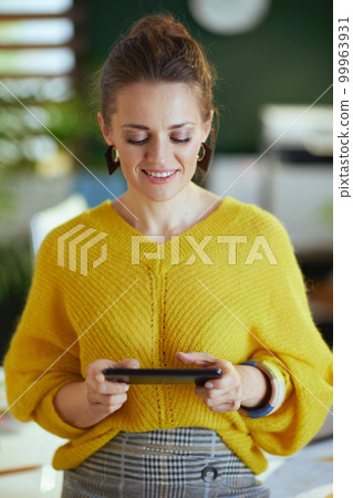 smiling business owner woman in green office using smartphone 99963931