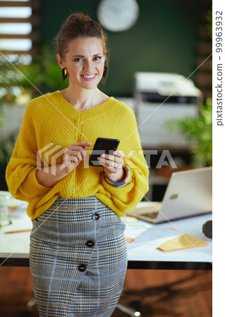 happy stylish business owner woman in green office using phone happy stylish business owner woman in green office using phone 99963932