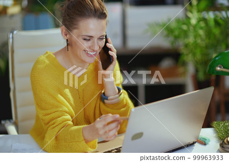 smiling business owner woman in green office talking on phone smiling business owner woman in green office talking on phone 99963933