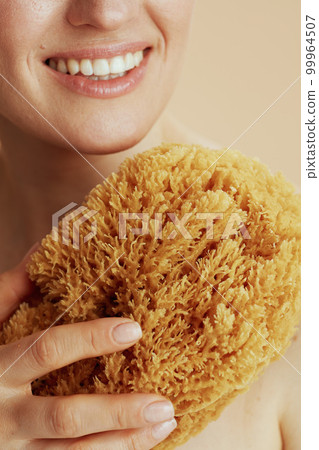 Closeup on young female with sea sponge 99964507