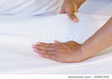Female Hand set up white bed sheet in bedroom or maid hands making bed in a hotel room 99965485