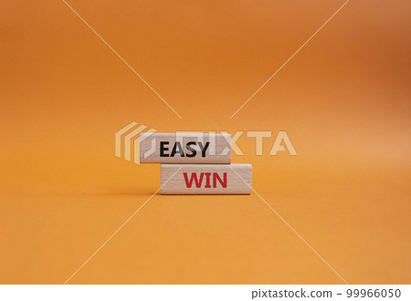 Easy win symbol. Wooden blocks with words Easy win. Beautiful orange background. Business and Easy win concept. Copy space. 99966050