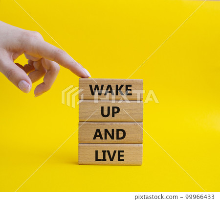 Wake up and live symbol. Wooden blocks with words Wake up and live. Beautiful yellow background. Businessman hand. Business and Wake up and live concept. Copy space. 99966433