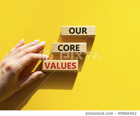 Our core values symbol. Concept words 'Our core values' on wooden blocks. Beautiful yellow background. Businessman hand. Business and Our core values concept. Copy space. 99966482
