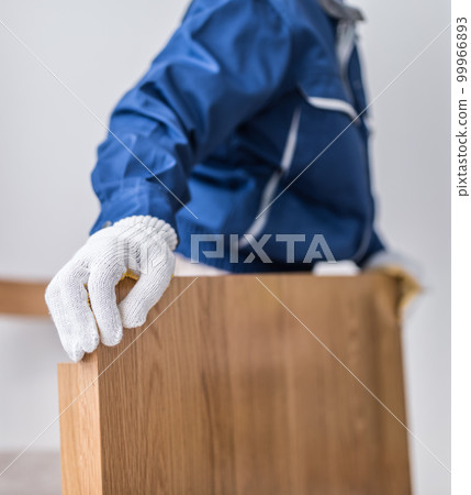 Woman in work clothes Unloading furniture 99966893