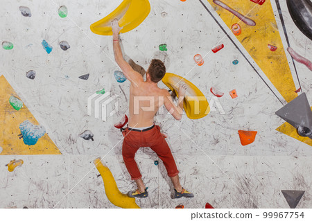 Young climber climbing on the boulder wall indoor, rear view, concept of extreme sports and bouldering 99967754