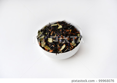 Black tea with spices in a glass cup on a white background. Delicious tea. Dry tea. Black tea with spices in a glass cup on a white background. Delicious tea. Dry tea. 99968076