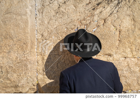 Jewish man in hat facing wall and praying 99968757