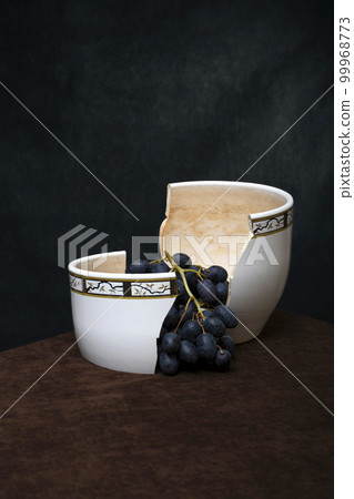 Still life with a branch of grapes in a broken vase Still life with a branch of grapes in a broken vase 99968773