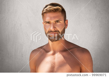 Horizontal portrait of handsome unshaven man with dark eyes, stylish hairdo staanding topless over grey background. Young muscular man with bristle looking directly into camera over copy space Horizontal portrait of handsome unshaven man with dark eyes, stylish hairdo staanding topless over grey background. Young muscular man with bristle looking directly into camera over copy space 99969071