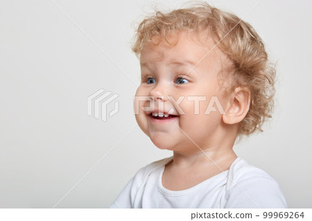 Little baby boy with curly blond hair laughing while looking attentively away wile posing isolated over white background, excited male child sees something interesting, copy space for promo. Little baby boy with curly blond hair laughing while looking attentively away wile posing isolated over white background, excited male child sees something interesting, copy space for promo. 99969264