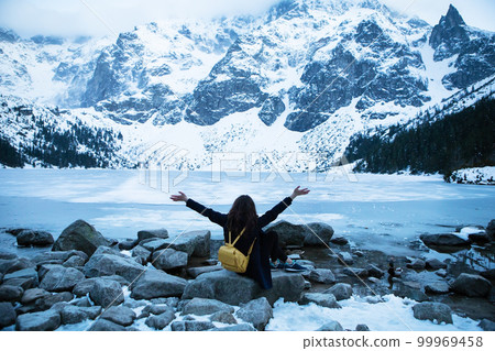 Picturesque and beautiful view of the mountains. Sea eye. The girl is sitting on a stone. Picturesque and beautiful view of the mountains. Sea eye. The girl is sitting on a stone. 99969458