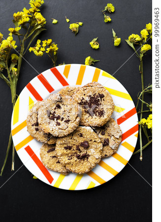 Oatmeal cookies with chocolate on a plate with bright yellow flowers. Oatmeal cookies with chocolate on a plate with bright yellow flowers. 99969463