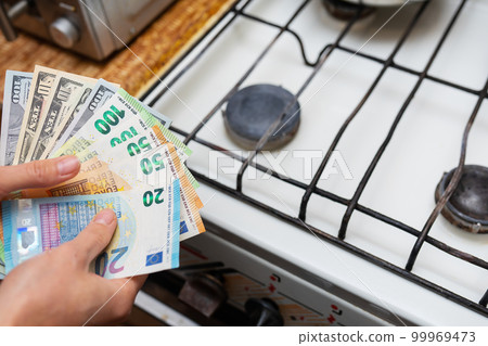Payment of utility bills, calculations on a calculator. Euro and dollar bills lie near a burning gas burner. The concept of increasing the cost of natural gas supply and payment. Energy crisis, top 99969473