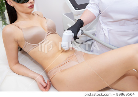 The process of laser hair removal of the female body, the abdomen area. Professional and safe cosmetology. Body care concept. The process of laser hair removal of the female body, the abdomen area. Professional and safe cosmetology. Body care concept. 99969504