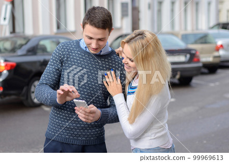 girl blond and guy looking something in the mobile phone and smi 99969613
