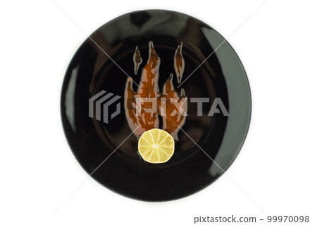 super hot dried lime slice enveloped in flames drawn with a spicy chili sauce on a black plate , isolated on white super hot dried lime slice enveloped in flames drawn with a spicy chili sauce on a black plate , isolated on white 99970098