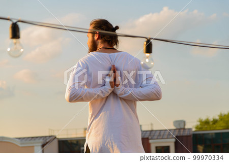 man on the roof doing yoga on the background of the setting sun man on the roof doing yoga on the background of the setting sun 99970334