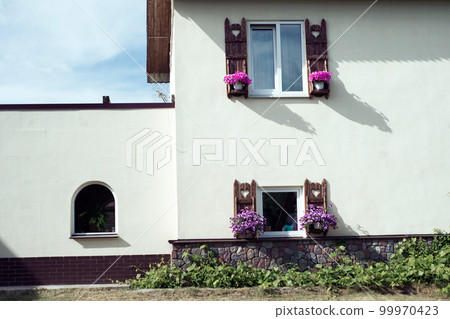 two windows with flower pots on the facade of the building 99970423