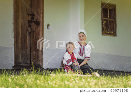mother and daughter sitting near the house 99971198