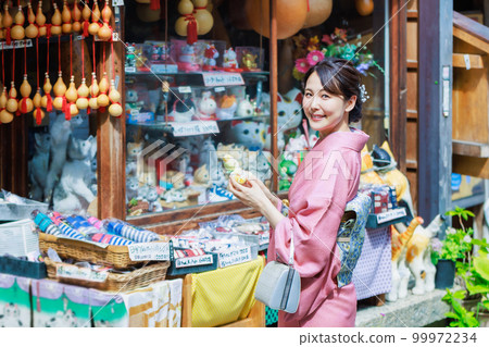 一位穿著和服的年輕女子在旅遊景點尋找紀念品 99972234
