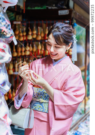 一位穿著和服的年輕女子在旅遊景點尋找紀念品 99972235