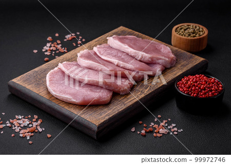 Fresh juicy pork on a wooden cutting board with spices and salt 99972746