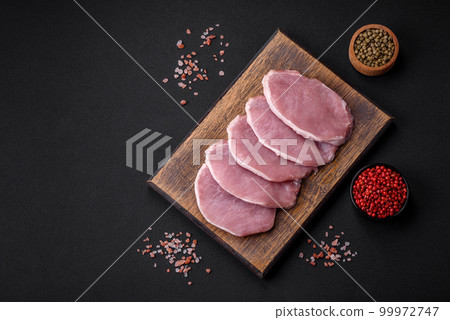 Fresh juicy pork on a wooden cutting board with spices and salt Fresh juicy pork on a wooden cutting board with spices and salt 99972747