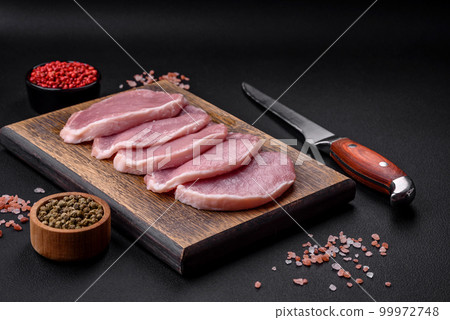 Fresh juicy pork on a wooden cutting board with spices and salt 99972748