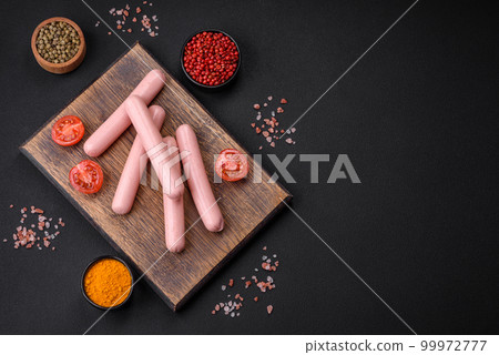 Boiled sausages on a wooden cutting board with tomatoes, spices and salt Boiled sausages on a wooden cutting board with tomatoes, spices and salt 99972777