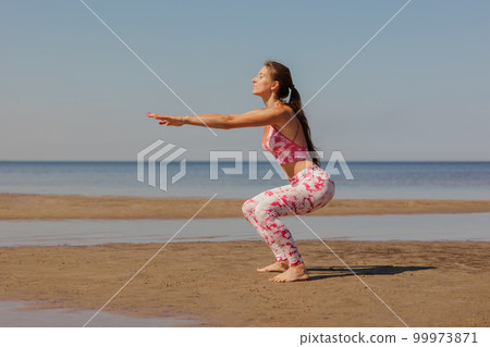 happy woman does yoga and fitness on sandy beach by sea. warm up stretching happy woman does yoga and fitness on sandy beach by sea. warm up stretching 99973871