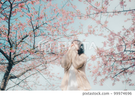 Photo of a woman listening to music with a cherry blossom background 99974696