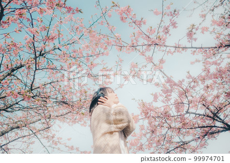Photo of a woman listening to music with a cherry blossom background 99974701