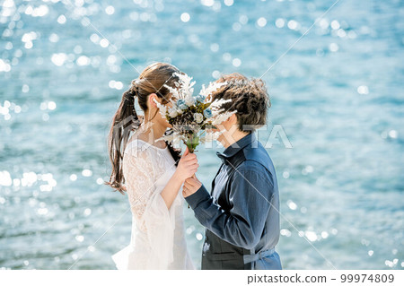 Bride and groom holding a bouquet and looking at each other Bride and groom holding a bouquet and looking at each other 99974809