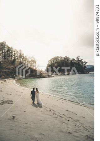 Bride and groom happily walking on the beach Bride and groom happily walking on the beach 99974831