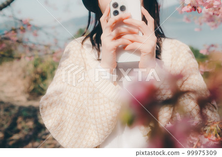 Photo of a woman listening to music with a cherry blossom background Photo of a woman listening to music with a cherry blossom background 99975309