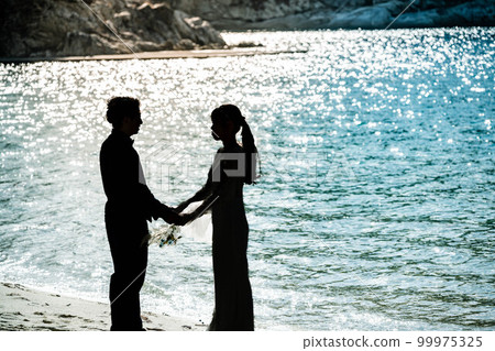 Bride and groom looking at each other on the beach 99975325