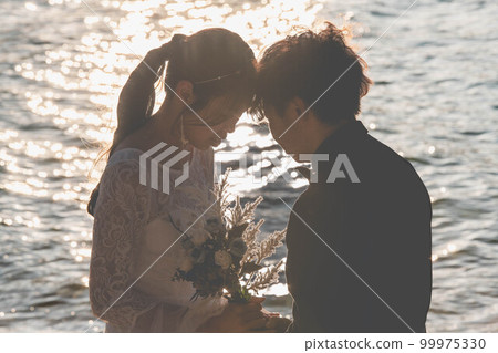 Bride and groom looking at each other on the beach 99975330