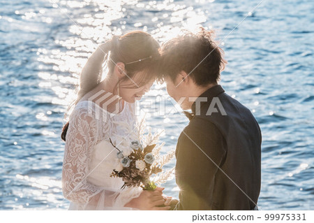 Bride and groom looking at each other on the beach Bride and groom looking at each other on the beach 99975331