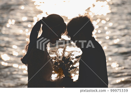Bride and groom looking at each other on the beach 99975339