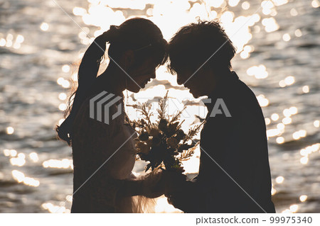 新娘和新郎在沙灘上互相看著對方 99975340