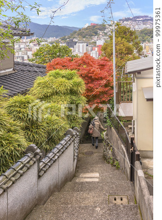 [Kyushu/Nagasaki] An elderly woman descending a narrow and steep staircase in a residential area near Kazagashira Park in autumn. 99975361