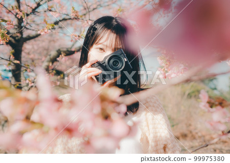 櫻花背景下手持微單相機的女性照片 櫻花背景下手持微單相機的女性照片 99975380