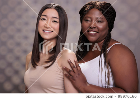 Beautiful young women with different body types and ethnicity posing together portrait. Asian and african american confident body positive beauty models wearing casual tops Beautiful young women with different body types and ethnicity posing together portrait. Asian and african american confident body positive beauty models wearing casual tops 99976166