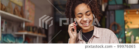 Smiling woman florist decorator listening music during break in floral studio 99976865