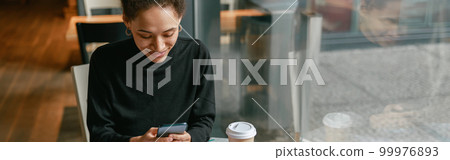 Woman architect use phone during working in cafe sitting near window. Distance work concept Woman architect use phone during working in cafe sitting near window. Distance work concept 99976893